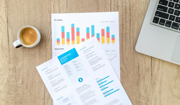 Wooden desk with documents, laptop, and coffee cup creating a modern office atmosphere.
